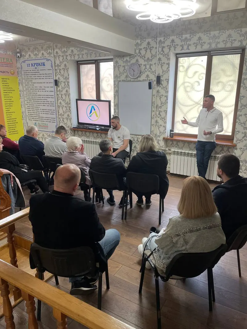 Групове заняття в залі центру ALTERA: учасники сидять півколом, консультант говорить біля вікна