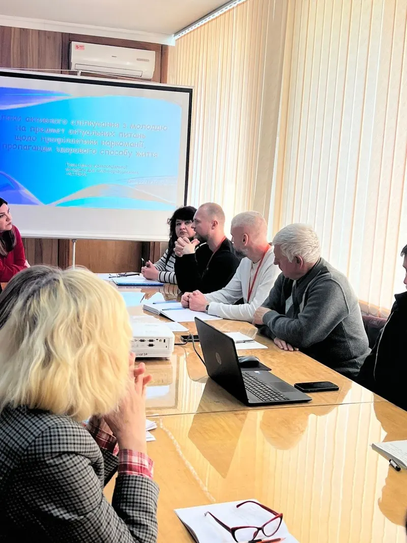 Семінар для фахівців: учасники за столом, на екрані презентація